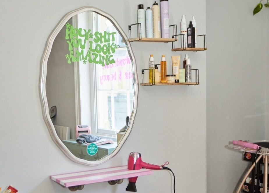 Elegant styling station at Wonderland Hair Cheltenham, Cheltenham, England, GB with mirror and hair products.