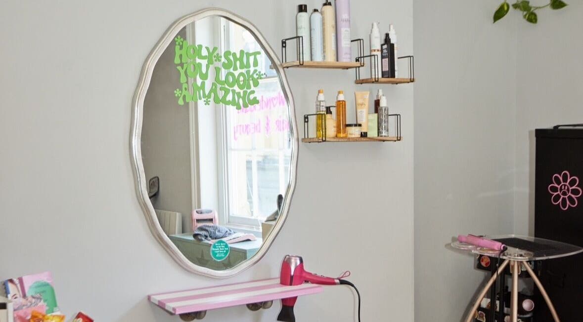 Elegant styling station at Wonderland Hair Cheltenham, Cheltenham, England, GB with mirror and hair products.