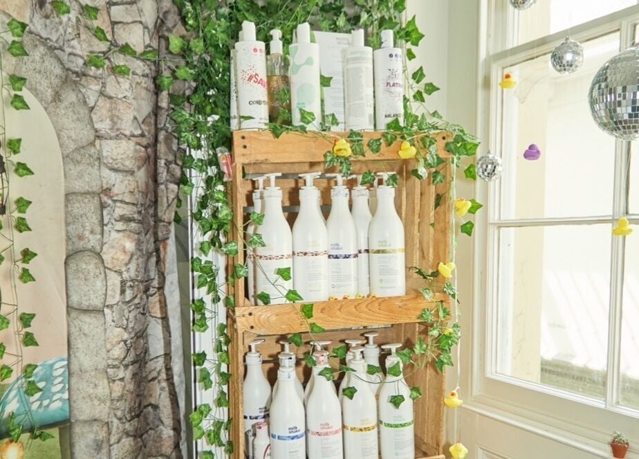 Eco-friendly product display at Wonderland Hair Cheltenham, Cheltenham, England, GB with lush green decor.