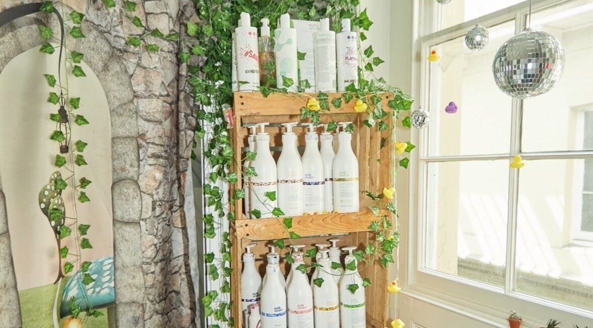 Eco-friendly product display at Wonderland Hair Cheltenham, Cheltenham, England, GB with lush green decor.