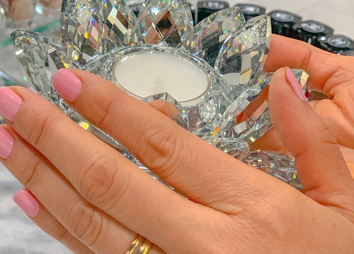 Elegant hands with pink nails holding a crystal at Prink Polished Nail Spa, Missouri City, Texas, US.