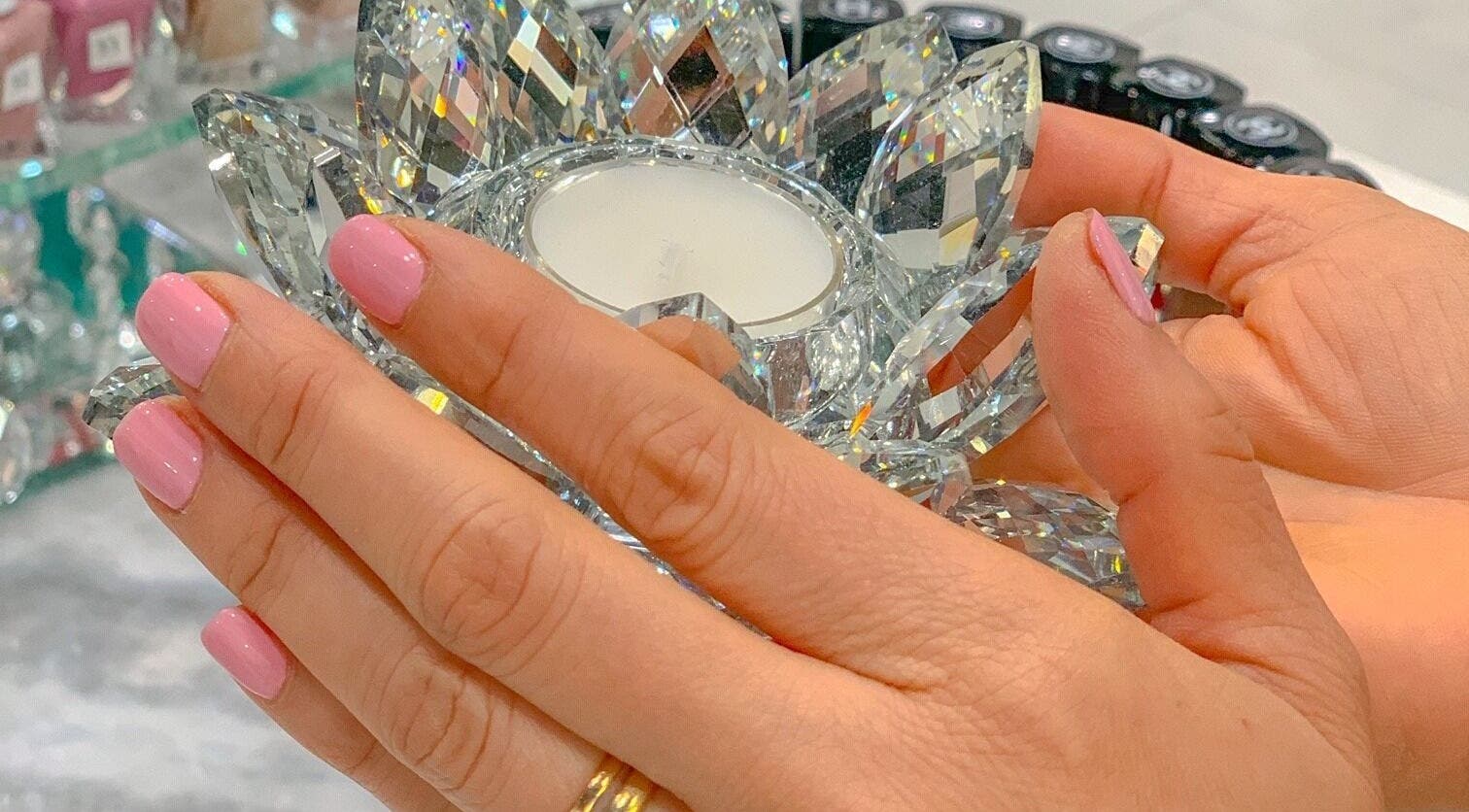 Elegant hands with pink nails holding a crystal at Prink Polished Nail Spa, Missouri City, Texas, US.