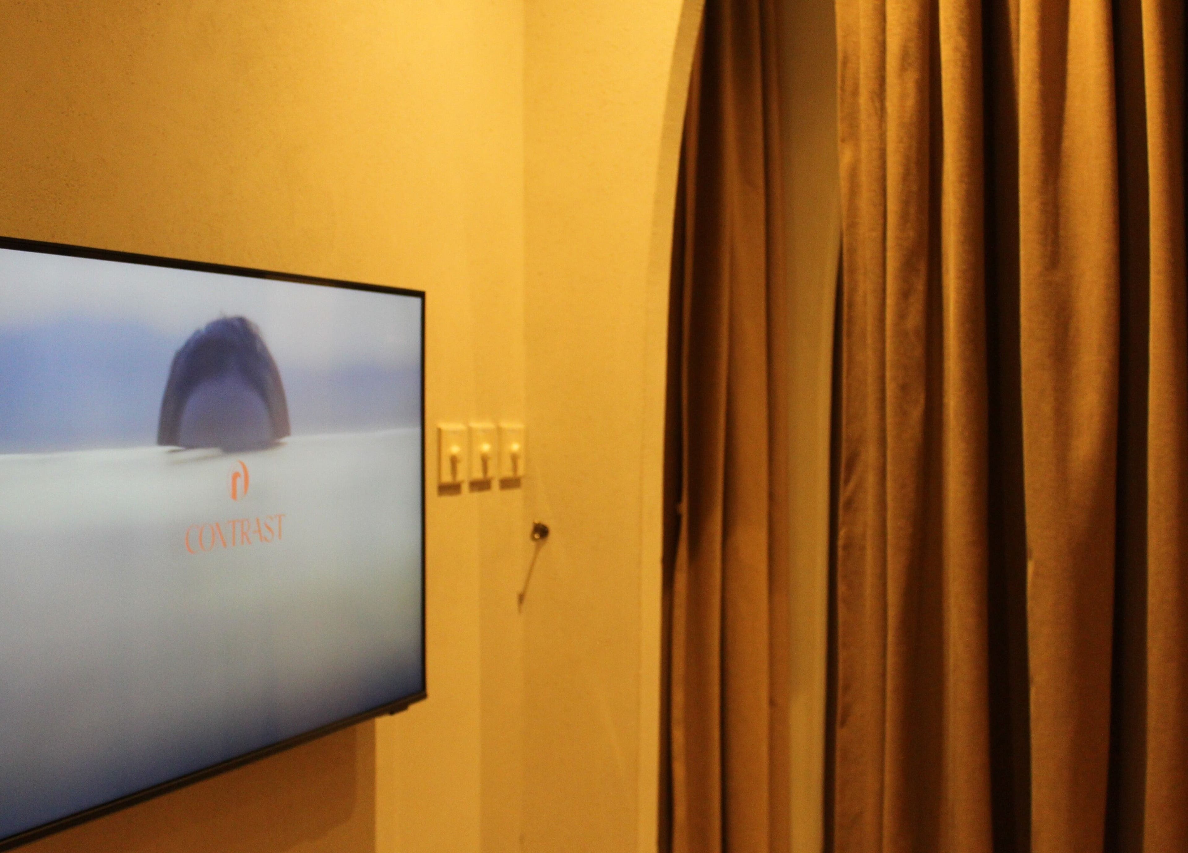 Elegant room at Contrast JVC, دبي, دبي, AE with a screen displaying serene visuals and plush curtains.