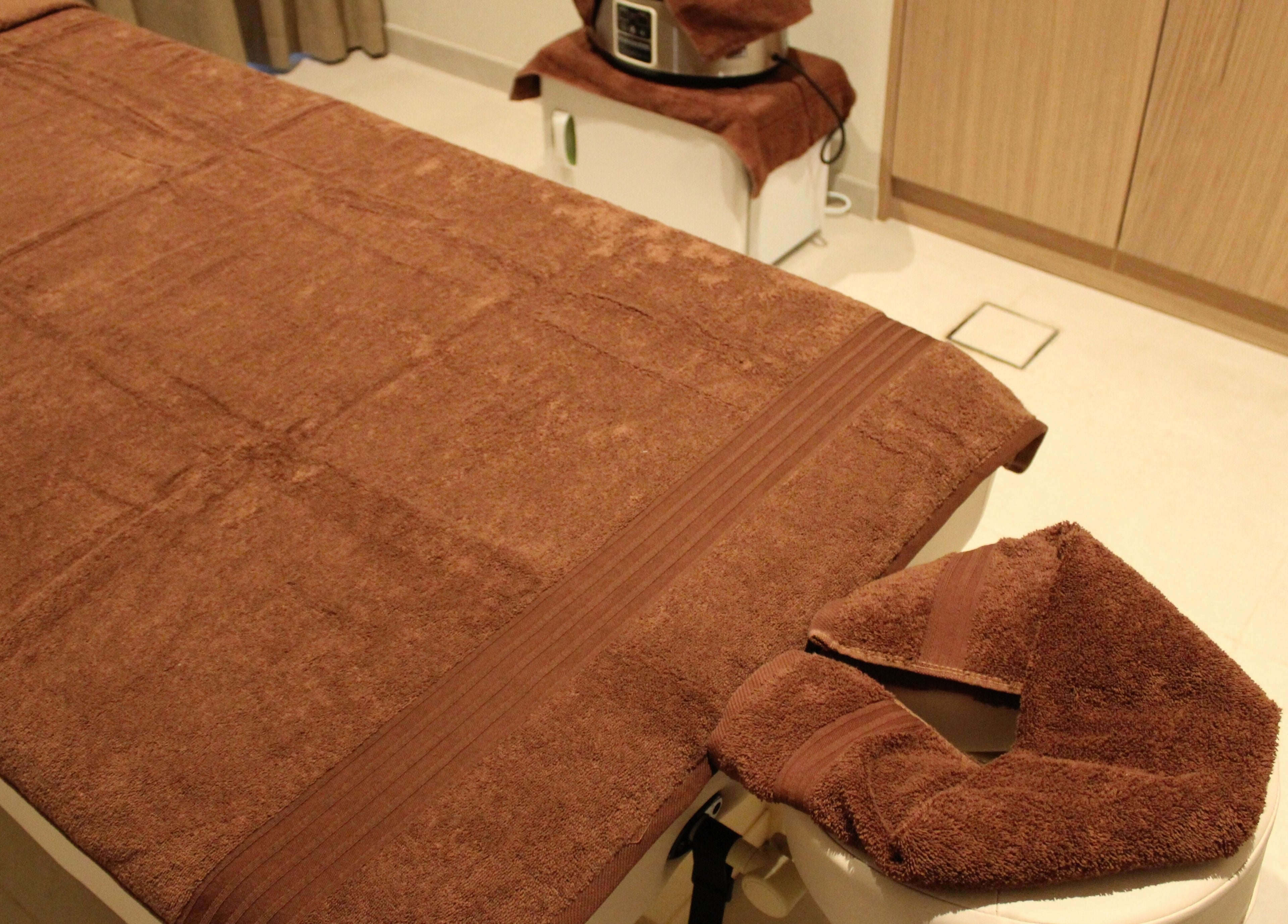 Massage table with brown towels at Contrast Dubai Creek Harbour, Dubai, Dubai, AE, offering serene wellness.