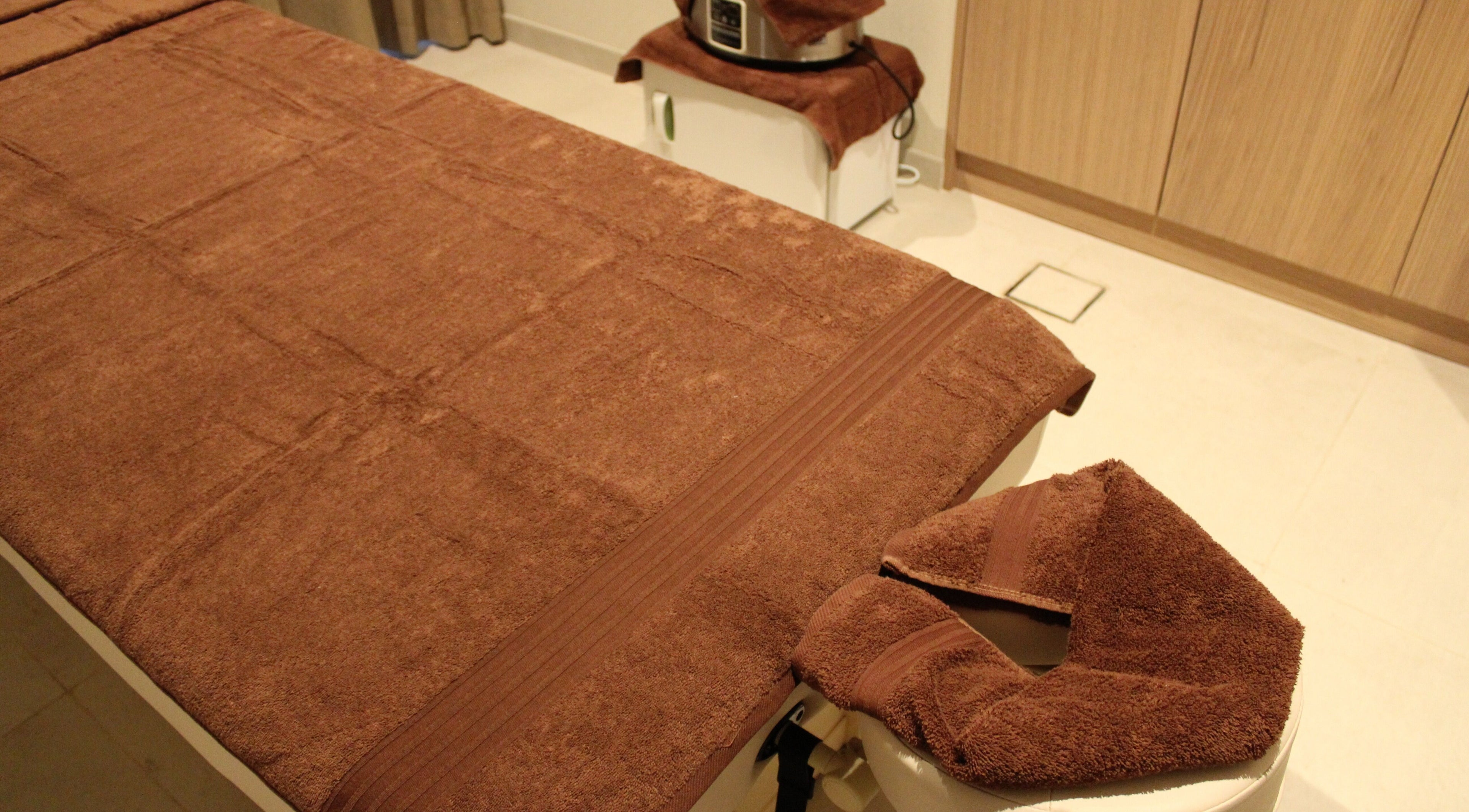 Massage table with brown towels at Contrast Dubai Creek Harbour, Dubai, Dubai, AE, offering serene wellness.