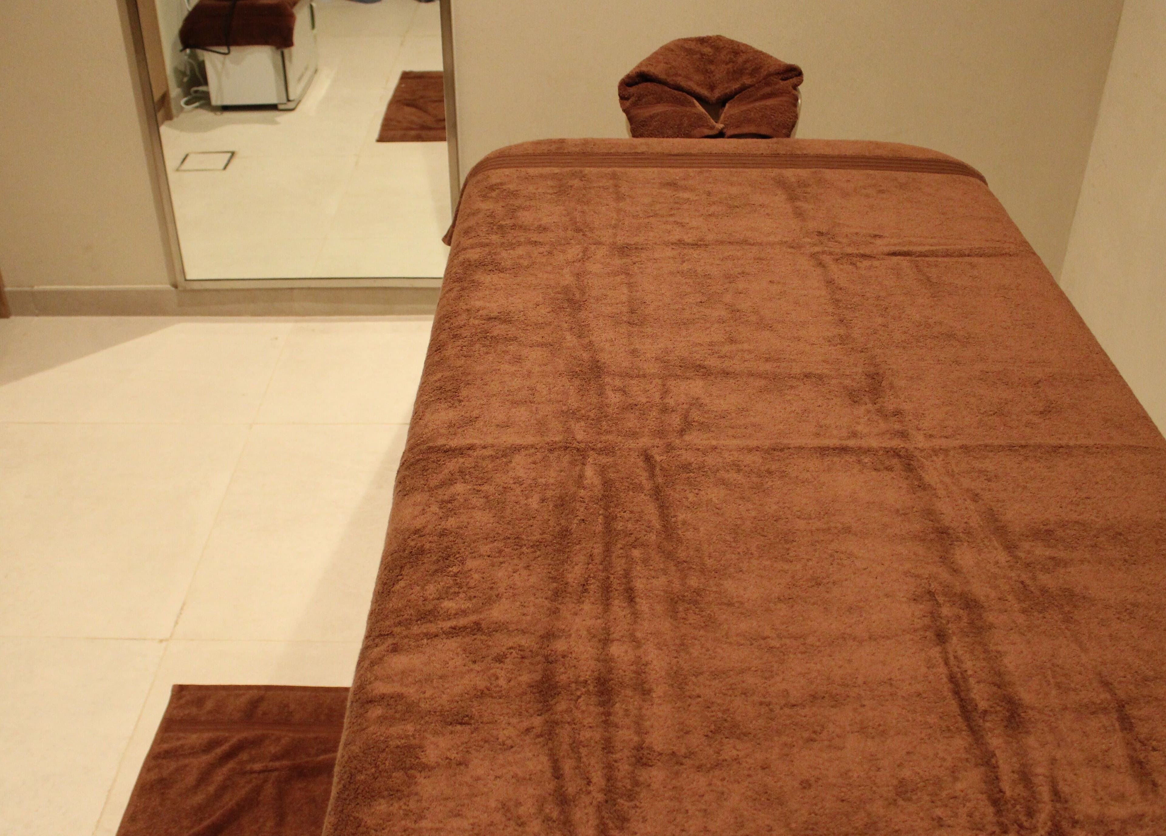 Luxurious massage room at Contrast Dubai Creek Harbour, Dubai, Dubai, AE with plush brown towel.