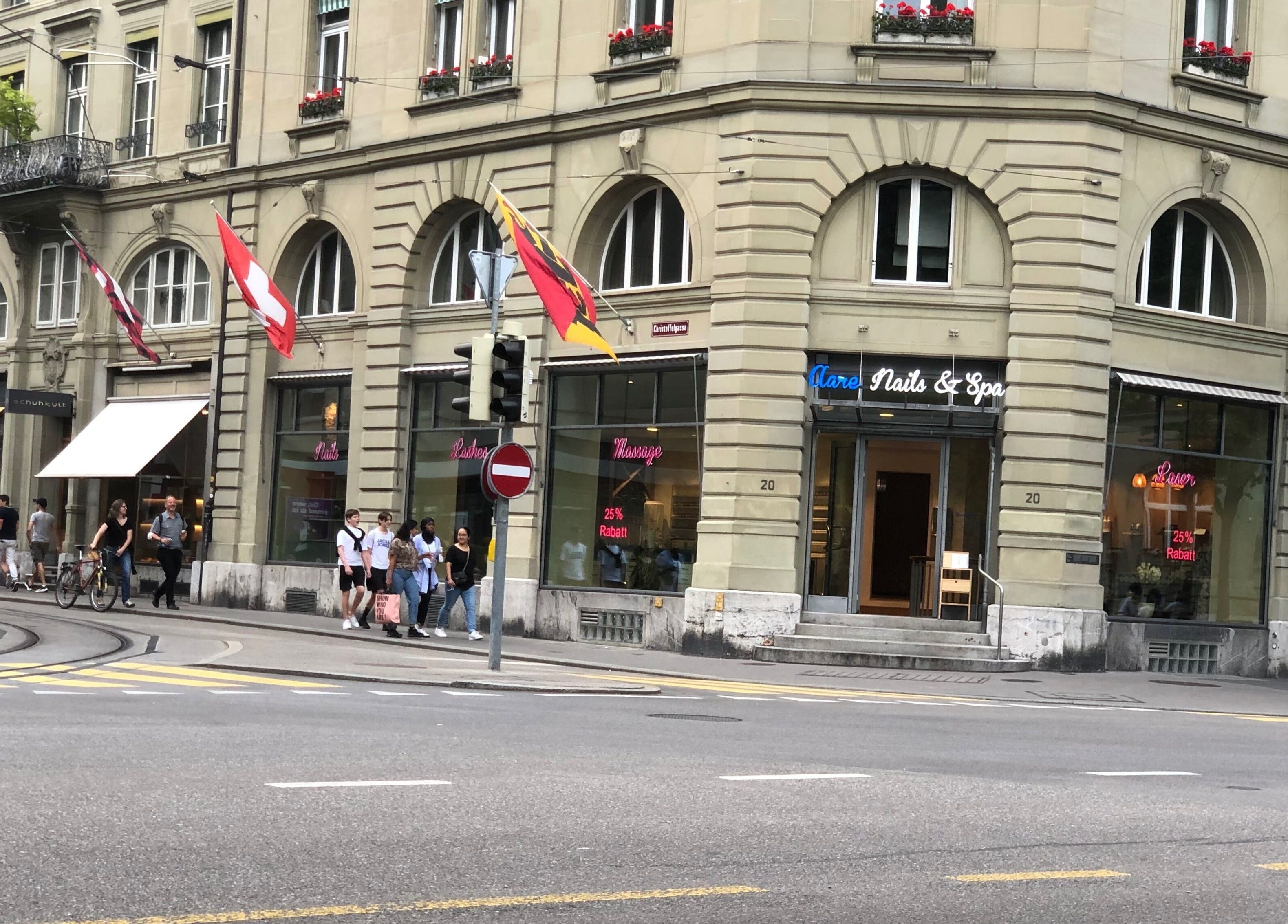 Eingang von Aare Nails & Spa, Bern, Bern, CH mit eleganter Fassade und Schweizer Flaggen im Hintergrund.