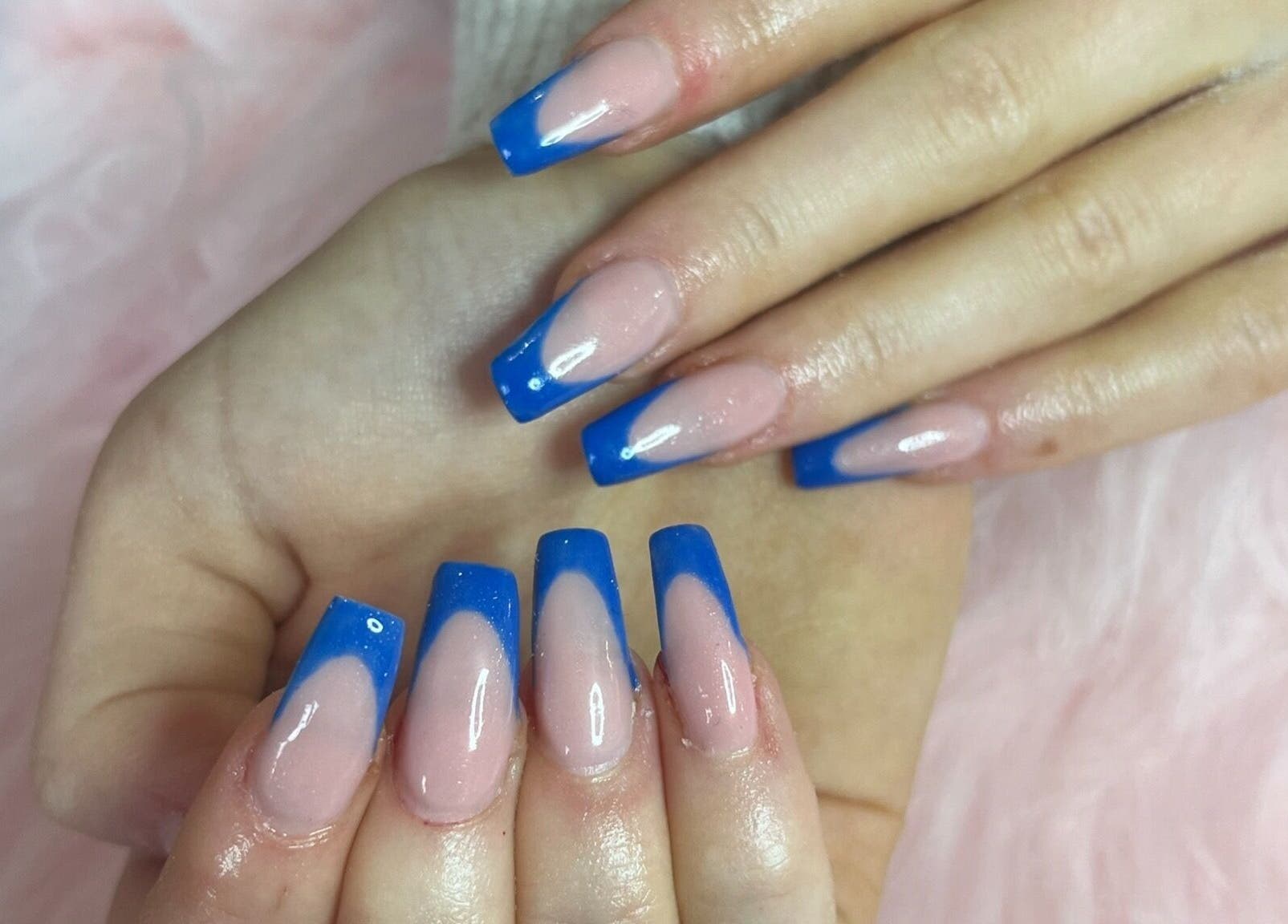 Elegant blue French manicure at Nails by Freya, Prestatyn, Wales, GB on soft pink background.