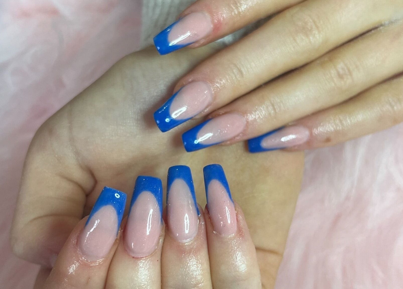 Elegant blue French manicure at Nails by Freya, Prestatyn, Wales, GB on soft pink background.