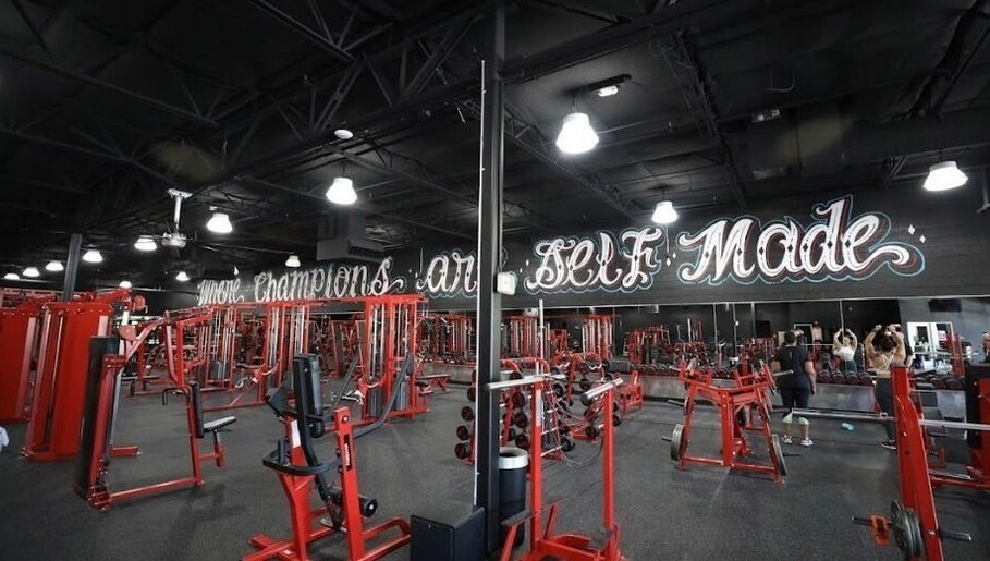 Spacious gym at Raneem Fitness in Scottsdale, Arizona, US, equipped with modern red machines and motivational decor.