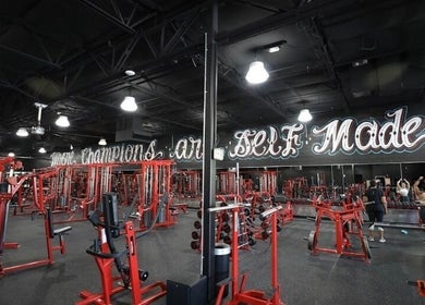 Spacious gym at Raneem Fitness in Scottsdale, Arizona, US, equipped with modern red machines and motivational decor.