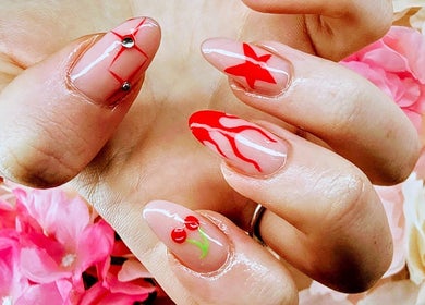 Elegant red nail art with floral backdrop at Cariad Beauty, Fauldhouse, Scotland, GB.