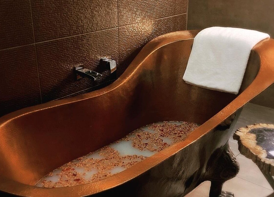 Elegant copper bathtub at Circa 1929 in Wagga Wagga, New South Wales, AU, with a towel and ambient lighting.