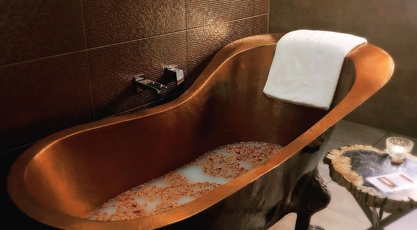 Elegant copper bathtub at Circa 1929 in Wagga Wagga, New South Wales, AU, with a towel and ambient lighting.