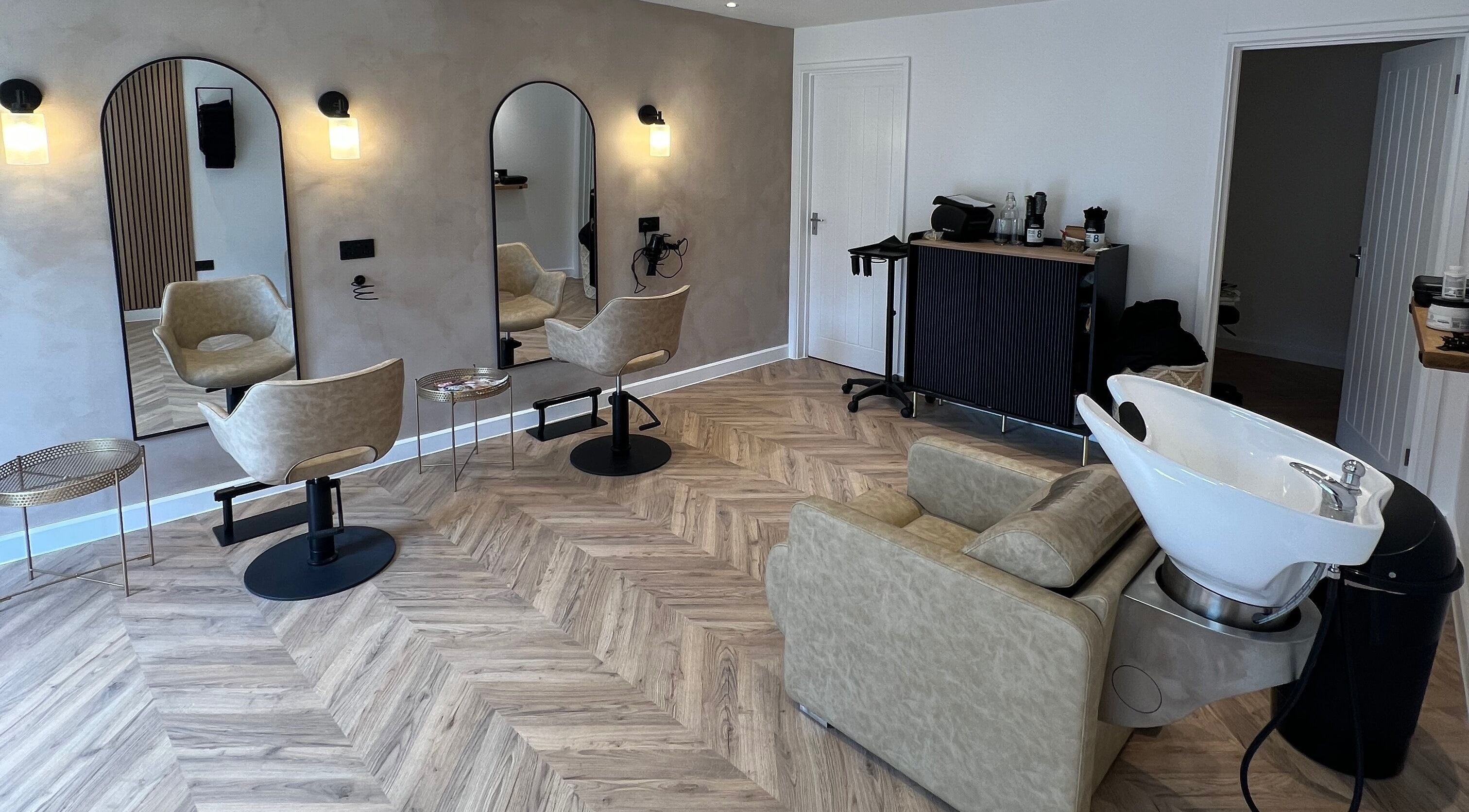 Modern salon interior at Rebecca Matthew Hair in Woking, England. Elegant styling chairs and mirrors displayed.