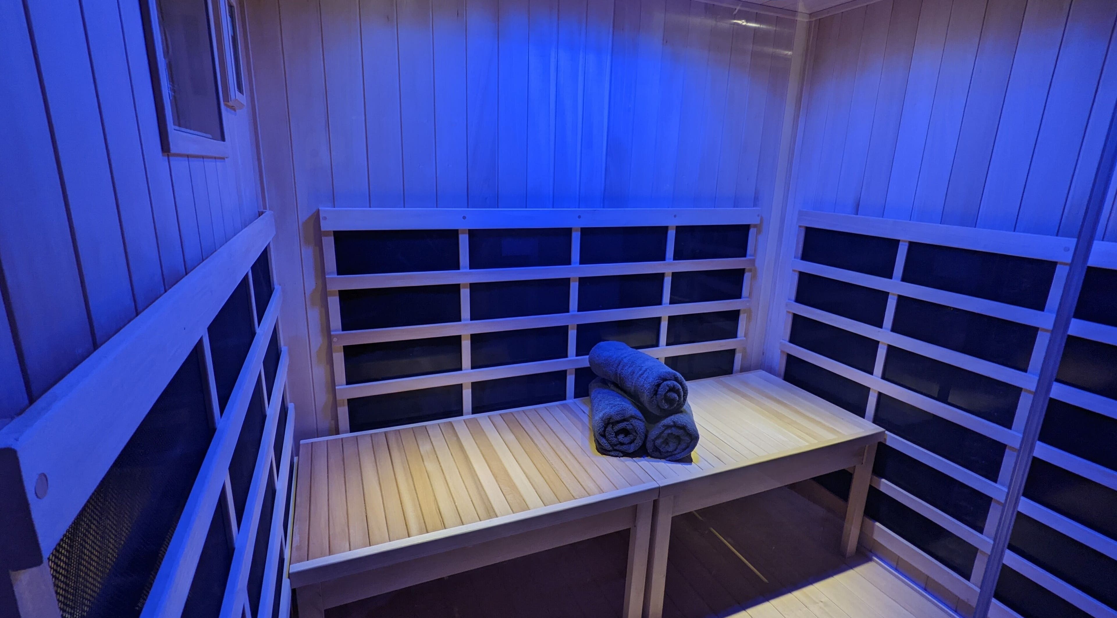 Relaxing sauna at The Wellness Spa, Watertown, Wisconsin, US, with folded towels on a wooden bench.