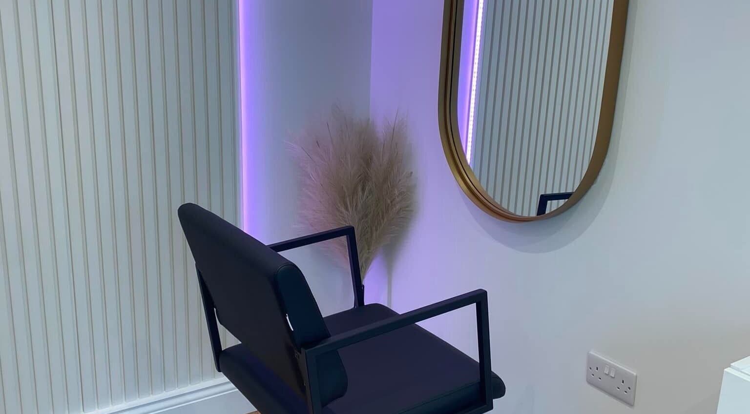 Modern beauty salon corner with chair and round mirror at Nóvara, Rochford, England, GB.