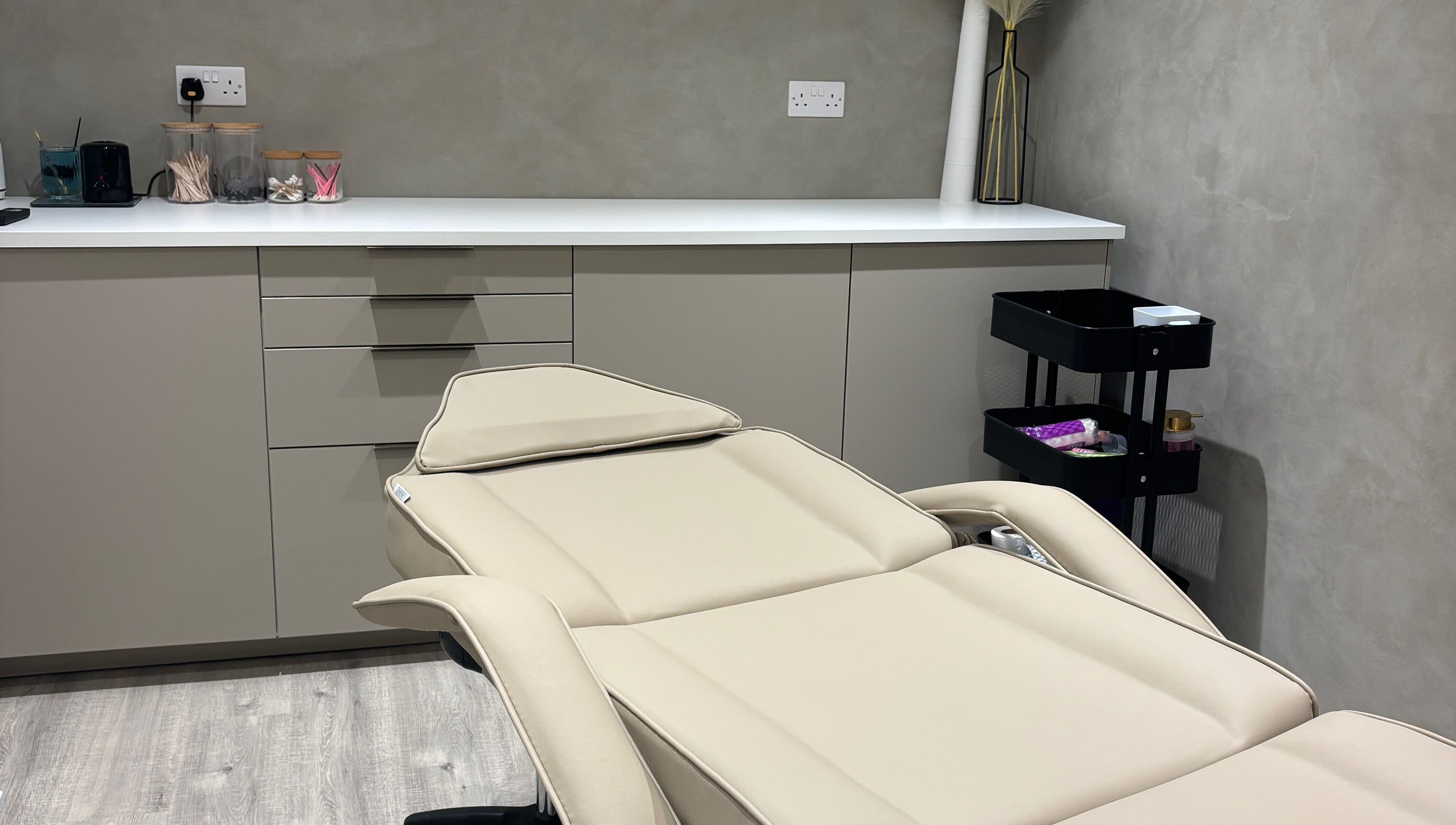 Luxurious treatment room at Nóvara in Rochford, England, GB, featuring a modern therapy bed and sleek decor.