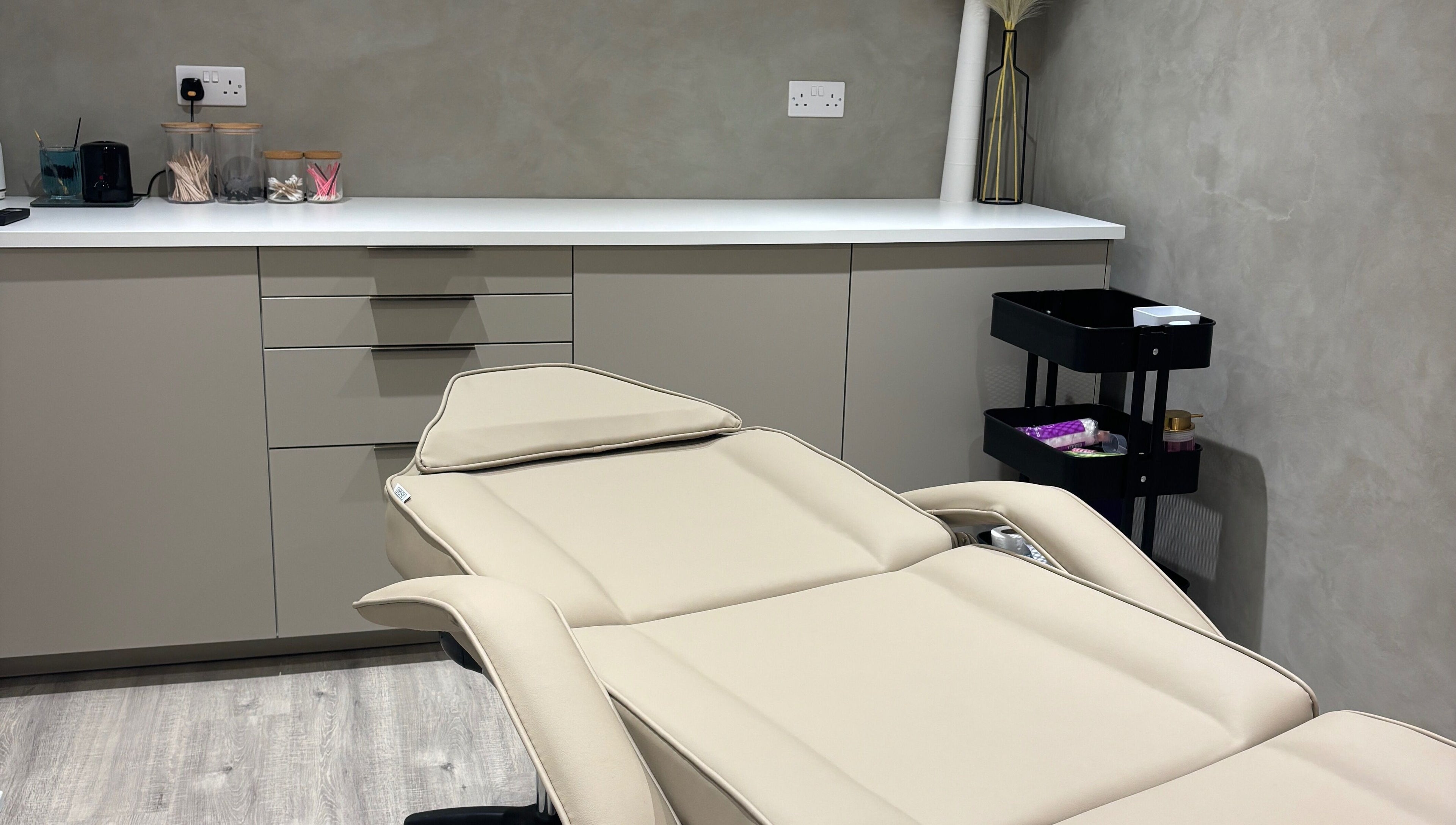 Luxurious treatment room at Nóvara in Rochford, England, GB, featuring a modern therapy bed and sleek decor.