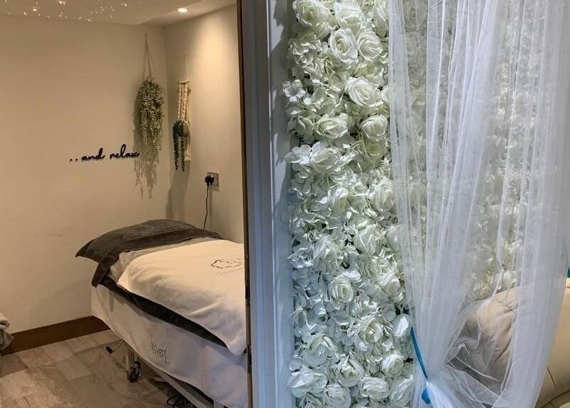 Relaxing treatment room at Achill Spa, Knowle, England, GB, featuring white floral decor and plush massage table.