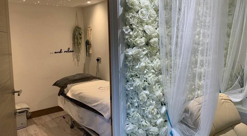 Relaxing treatment room at Achill Spa, Knowle, England, GB, featuring white floral decor and plush massage table.