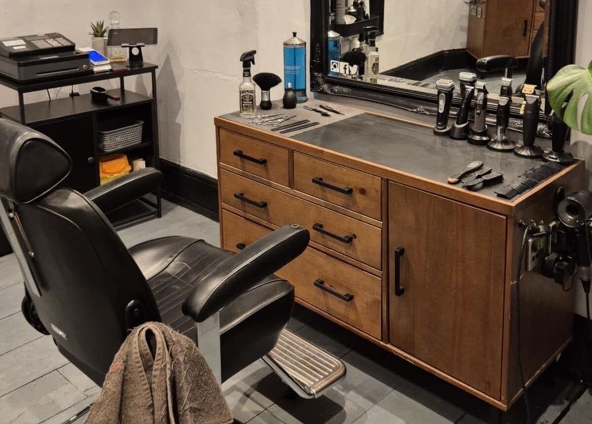 Elegant barber station at The Attic Barbershop in Norwich, England featuring sleek black chair and wooden counter.