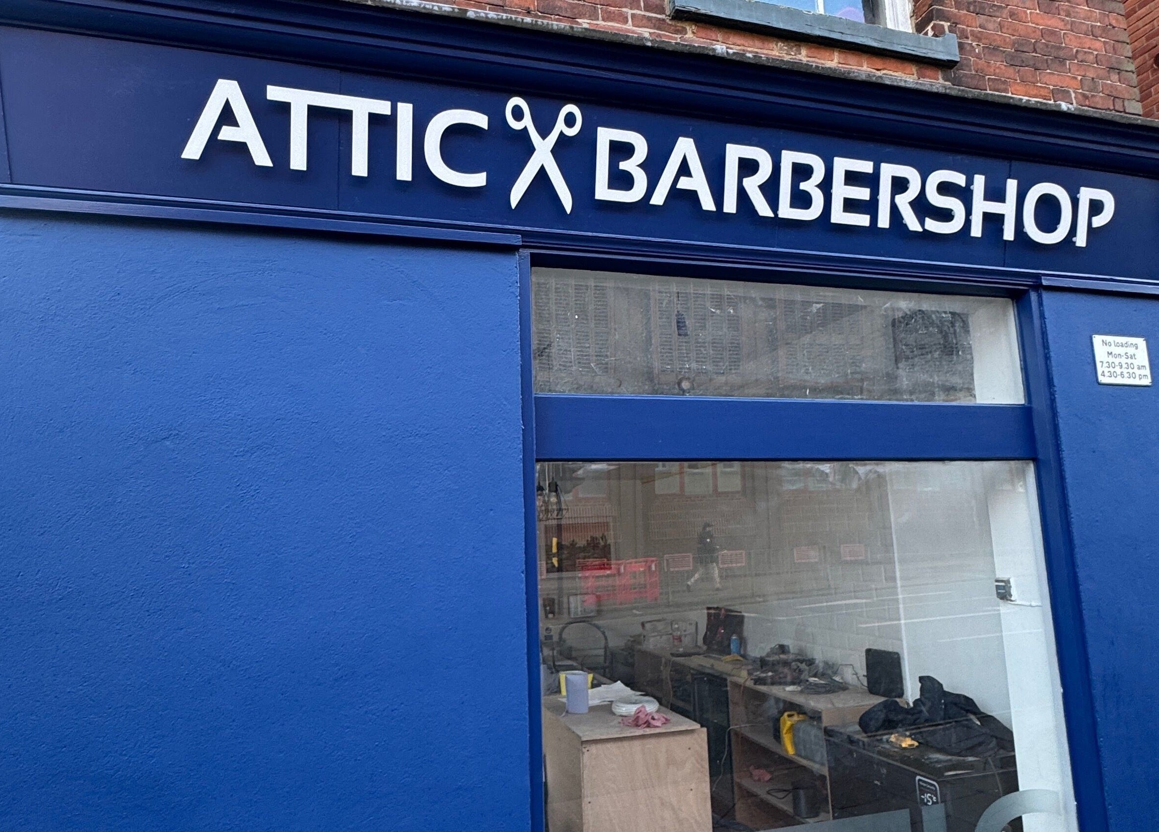 The Attic Barbershop in blue, Norwich, England, GB showcasing its stylish exterior signage.