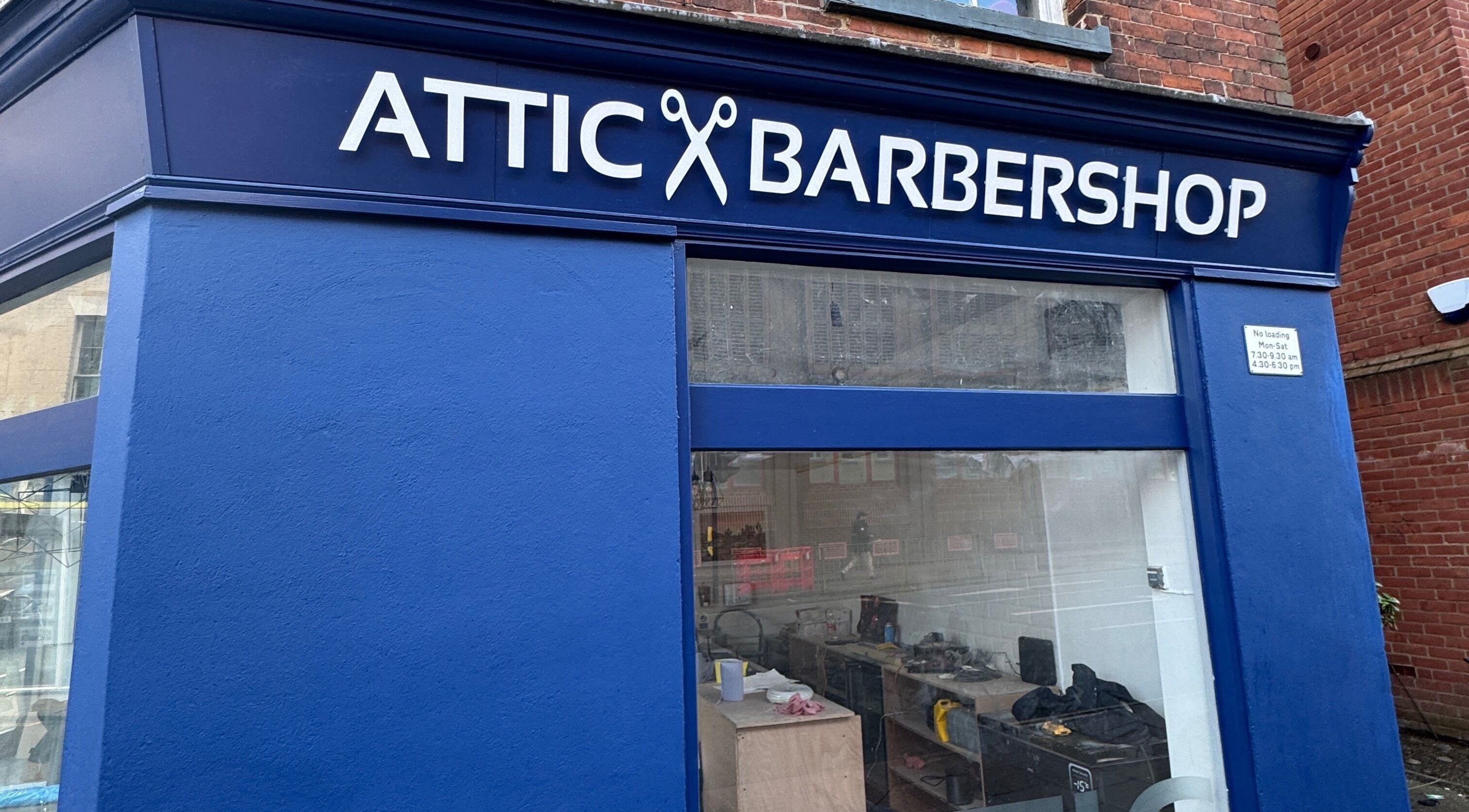 The Attic Barbershop in blue, Norwich, England, GB showcasing its stylish exterior signage.
