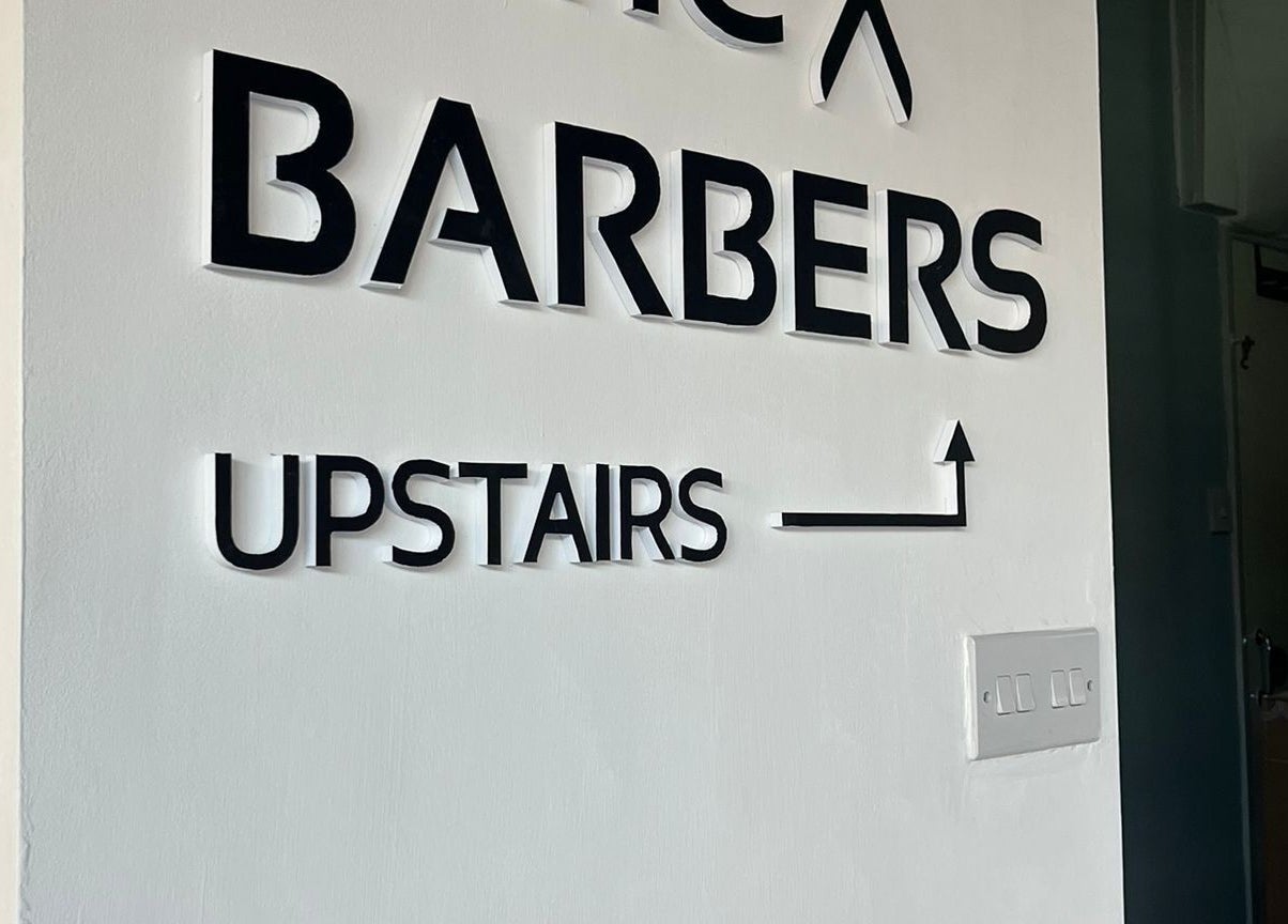 Entrance sign for The Attic Barbershop, Norwich, England, GB directing customers upstairs.