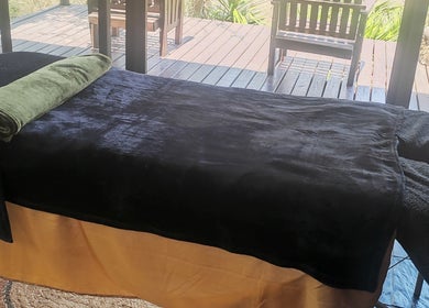 Relaxing massage table at Natural Beauty Salon And Spa, Hoedspruit, Gauteng, ZA, overlooking a tranquil garden deck.