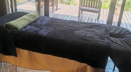 Relaxing massage table at Natural Beauty Salon And Spa, Hoedspruit, Gauteng, ZA, overlooking a tranquil garden deck.