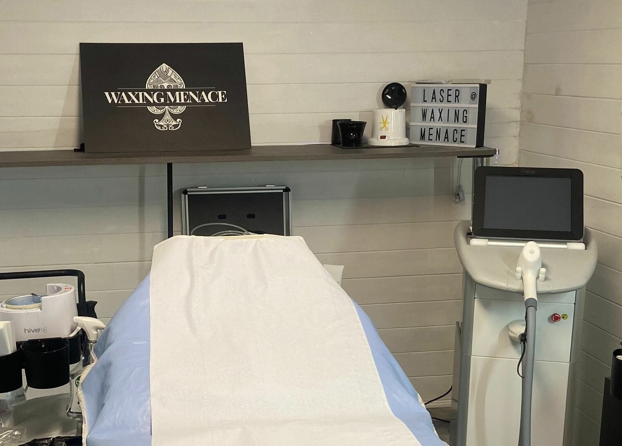 Modern waxing and laser setup at The Waxing Menace in Stevenage, England, GB showcasing equipment and treatment bed.