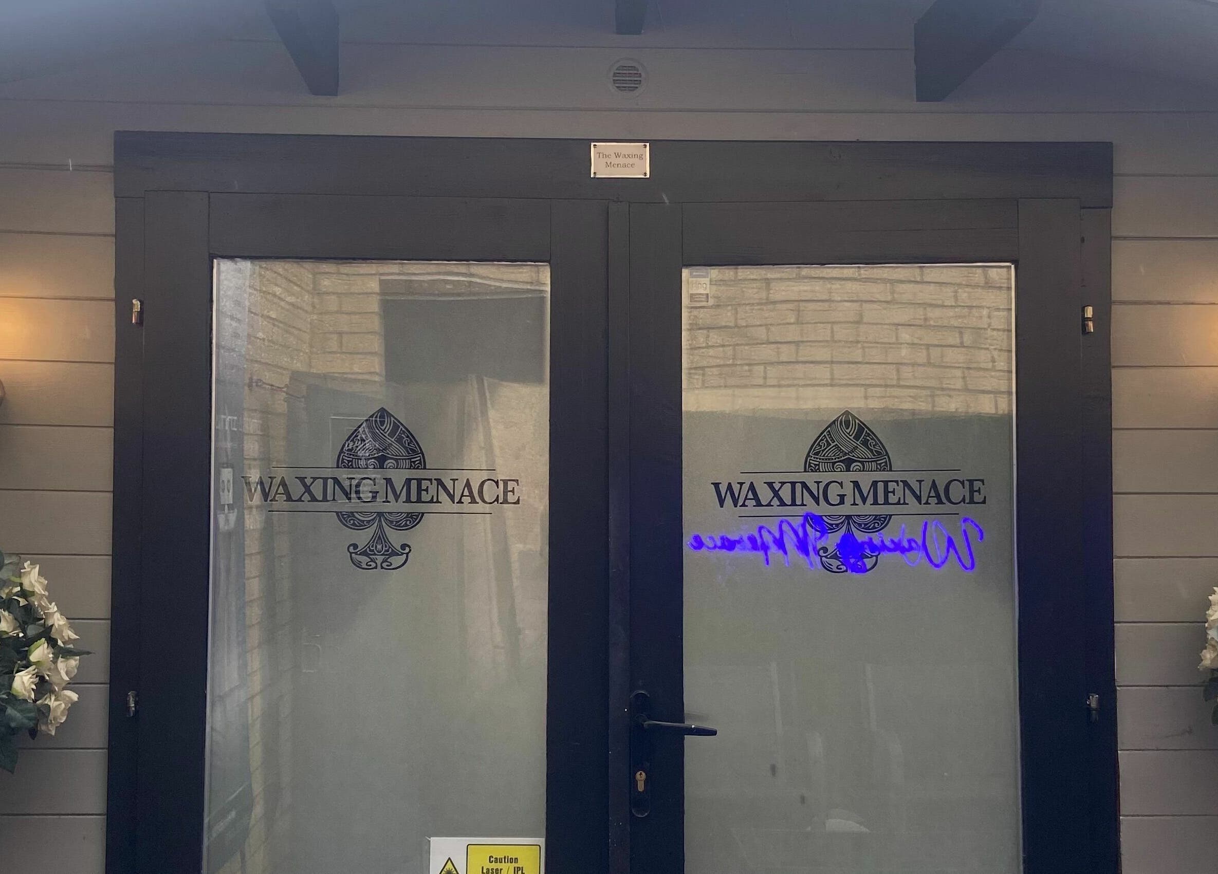 Entrance of The Waxing Menace in Stevenage, England, GB with elegant door design and floral arrangements.