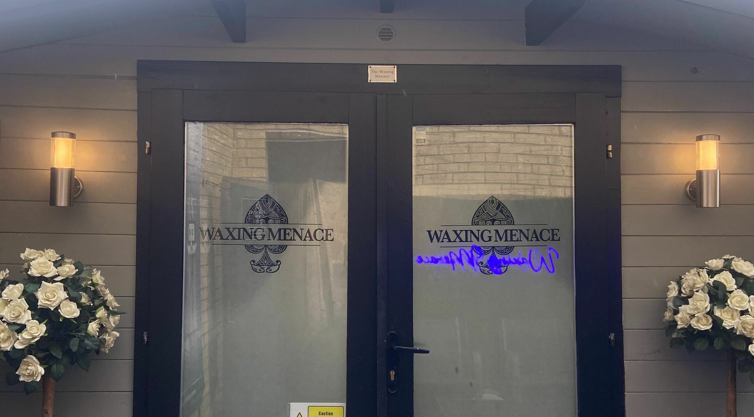 Entrance of The Waxing Menace in Stevenage, England, GB with elegant door design and floral arrangements.