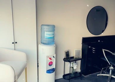Modern beauty salon interior at The Aesthetic Lounge, Bristol, England. Features stylish chairs and water cooler.
