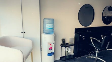 Modern beauty salon interior at The Aesthetic Lounge, Bristol, England. Features stylish chairs and water cooler.