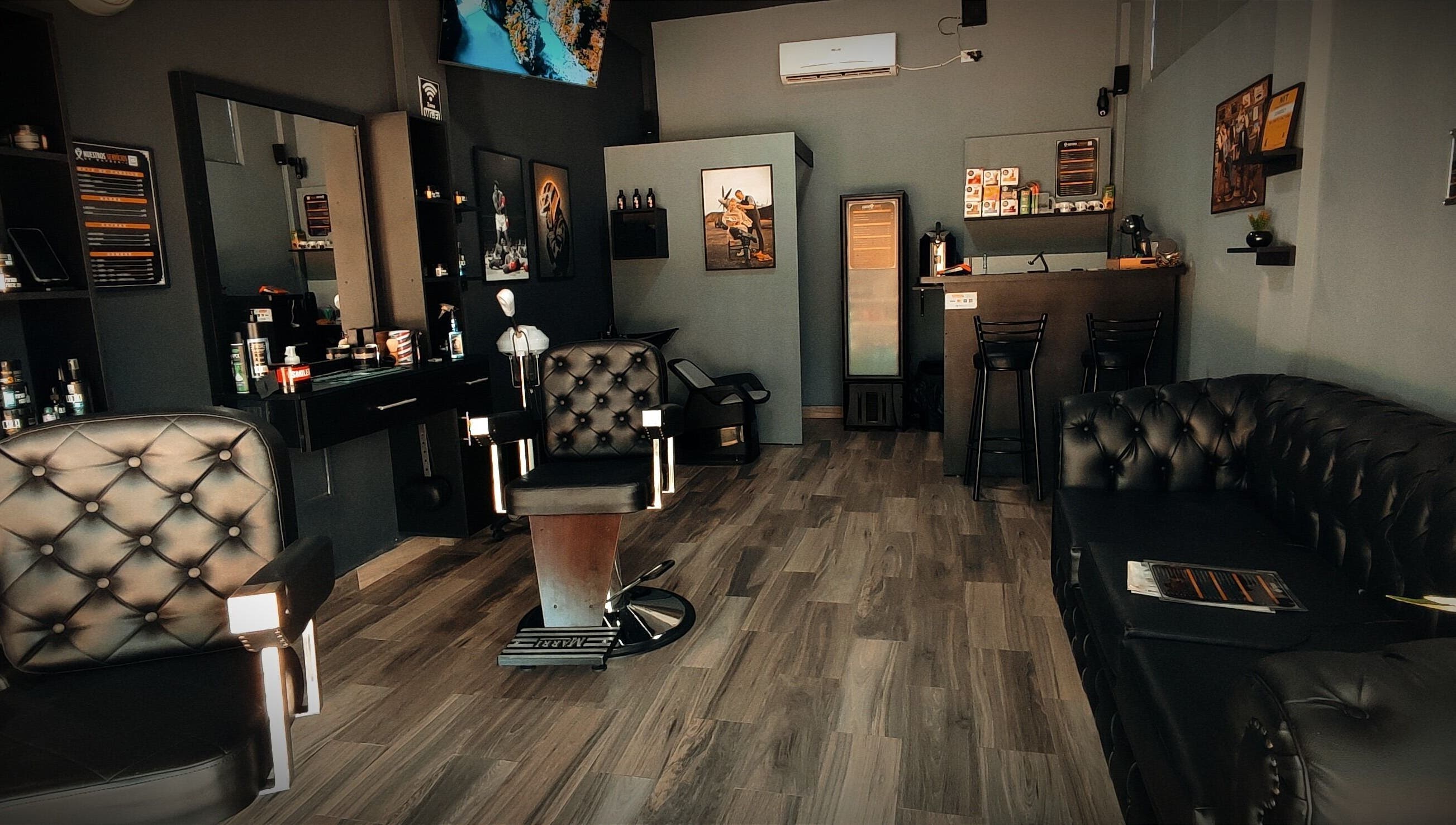 Interior moderno de Invictus Barbers & Coffee en Santa Cruz de la Sierra, BO, con sillas de cuero y decoración elegante.