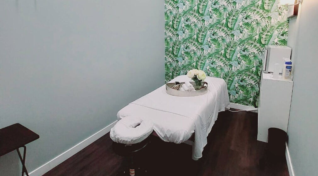 Relaxing massage room at Mica Spa Wellness in Vaughan, Ontario, CA with lush green wallpaper and serene decor.