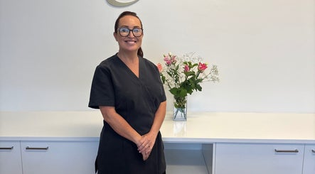 Staff member at The Retreat Room At GloMedispa, Grantham Farm, New South Wales, AU, with floral display.