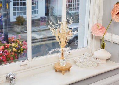 Bright window ledge at Cara Does Nails, Cowbridge, Wales, GB, adorned with flowers and ornaments.