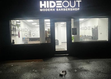 Entrance of Hideout barbershop in Glasgow, Scotland, GB, illuminated at night.