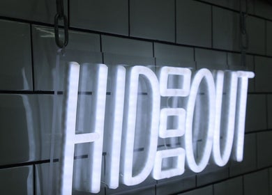 Bright neon sign spelling 'Hideout' against tiled wall in Glasgow, Scotland, GB spa venue.