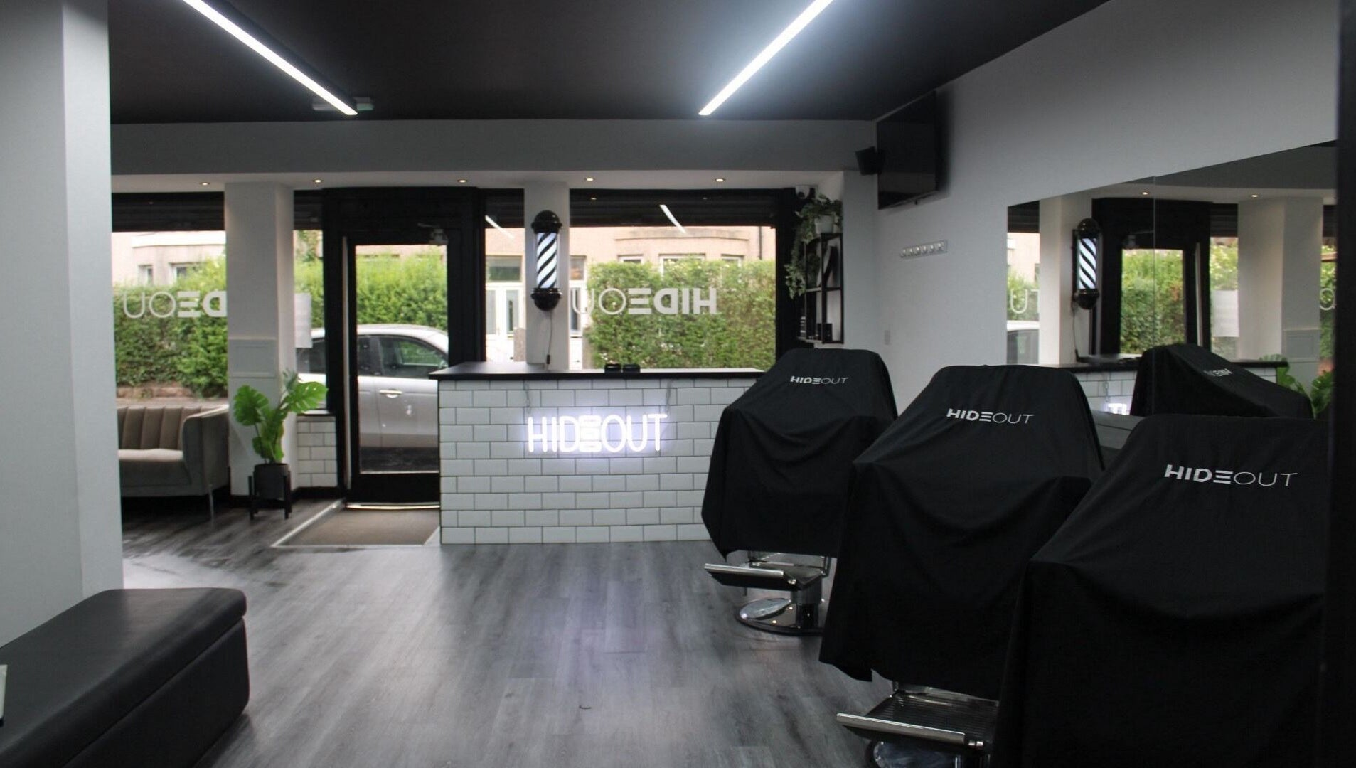 Modern interior of Hideout salon in Glasgow, Scotland, GB with sleek black chairs and a minimalist counter.