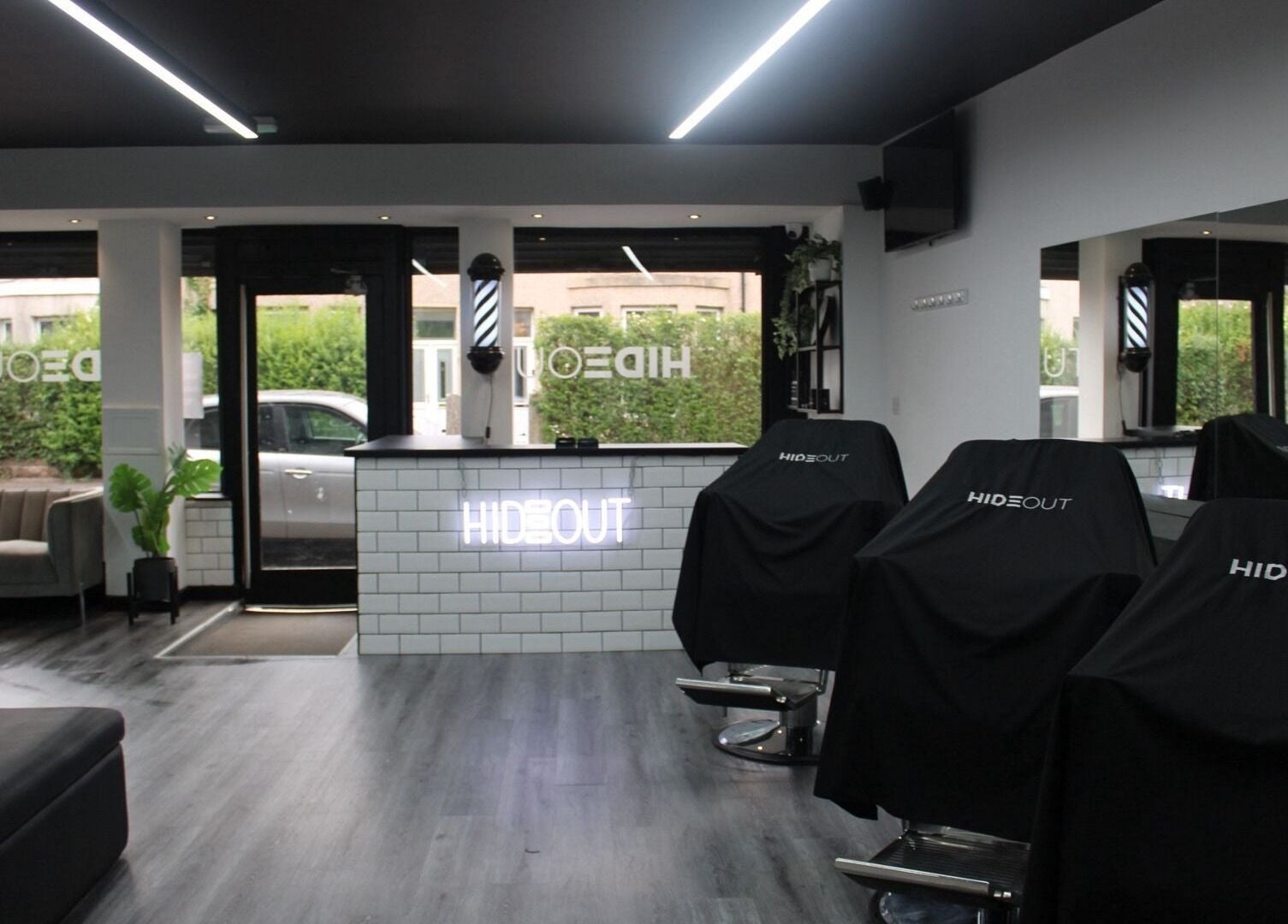 Modern interior of Hideout salon in Glasgow, Scotland, GB with sleek black chairs and a minimalist counter.
