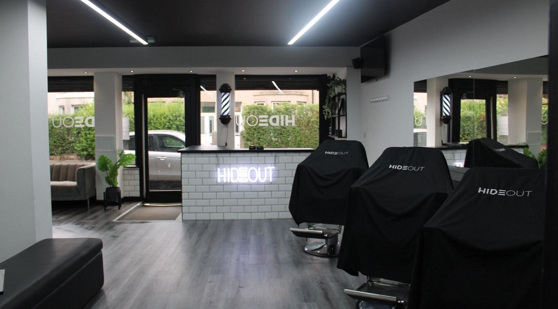 Modern interior of Hideout salon in Glasgow, Scotland, GB with sleek black chairs and a minimalist counter.