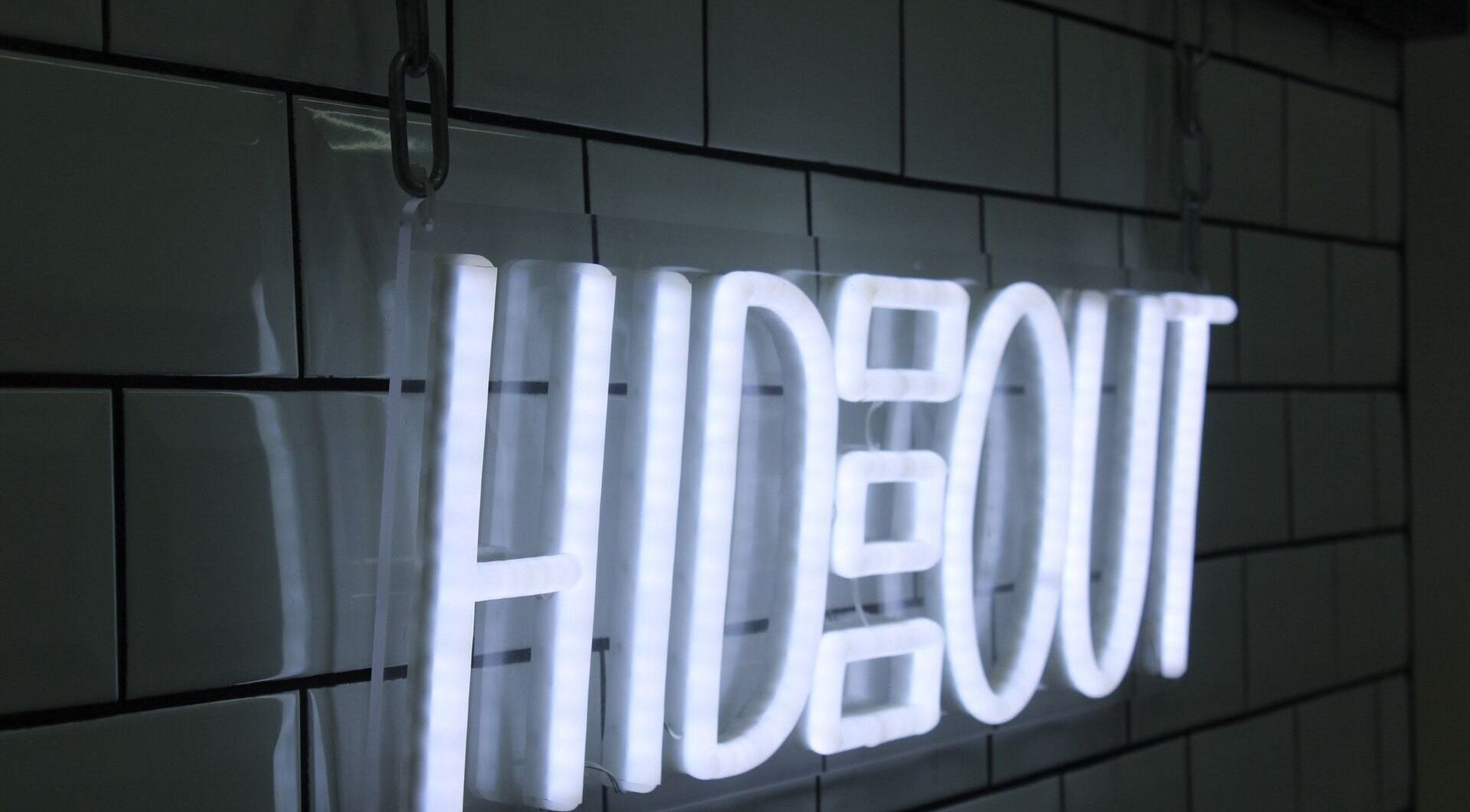 Illuminated Hideout sign on tiled wall at Hideout, Glasgow, Scotland, GB.