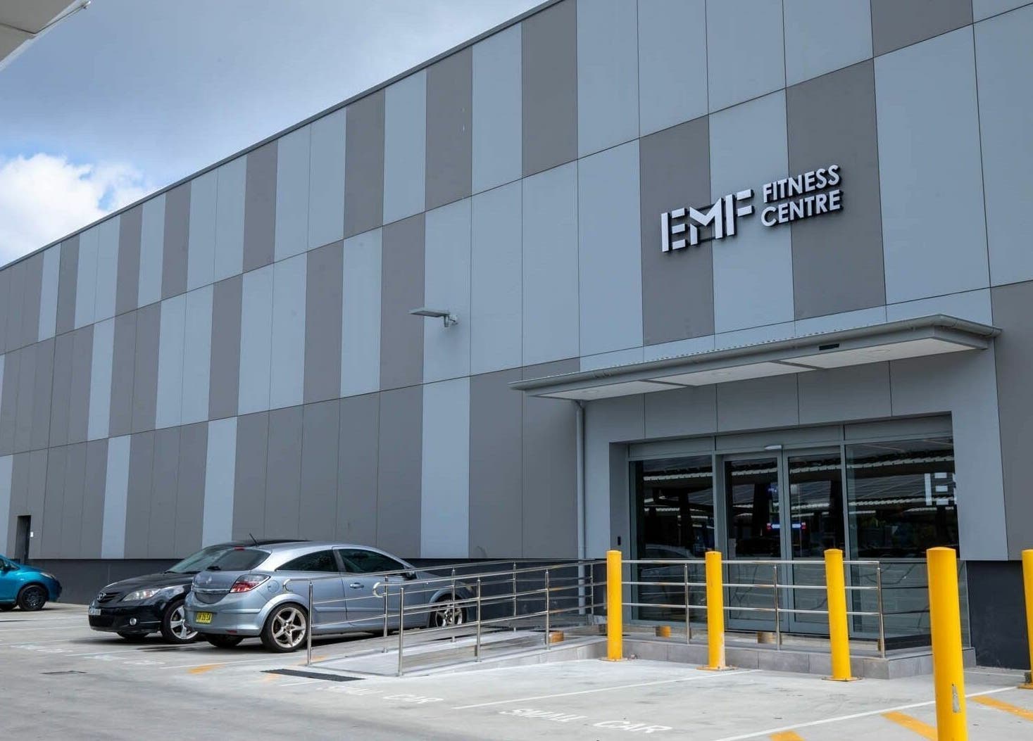 EMF Fitness Centre's modern exterior in Kotara, New South Wales, AU, with a parking area in view.