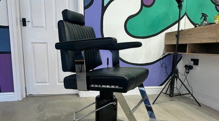 Modern barber chair at Blades Barbers in Hereford, England, GB with vibrant mural background.