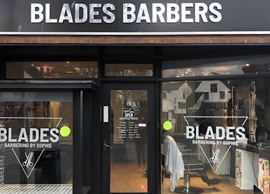 Front view of Blades Barbers shop in Hereford, England, GB, showcasing modern glass storefront.