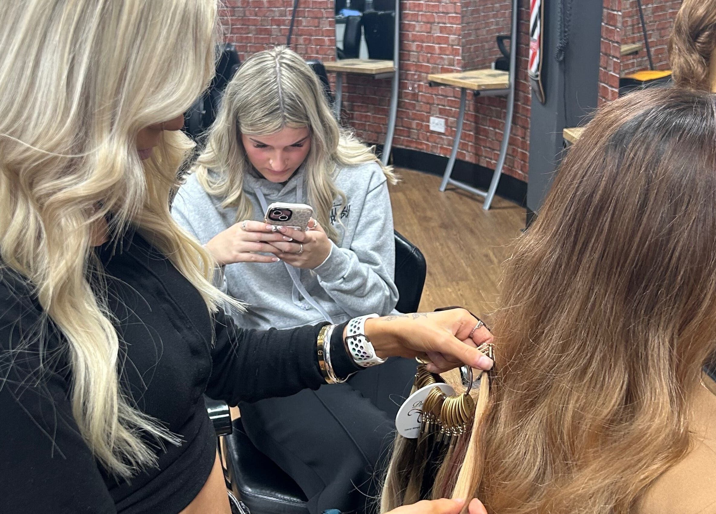 Stylists at Ksk Hair Academy in Lydney, England, GB perfecting a client's hair extension technique.